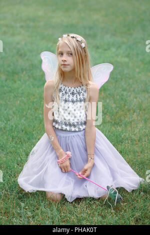 Portrait of smiling blonde blanc caucasien enfant kid girl with long hair wearing pink fairy wings et tutu jupe en tulle holding baguette magique. Heureux les natures mortes Banque D'Images
