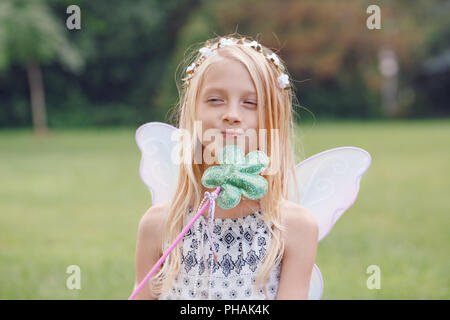 Portrait of smiling blonde blanc caucasien enfant kid girl with long hair wearing pink fairy wings et tutu jupe en tulle holding baguette magique, heureux les natures mortes Banque D'Images