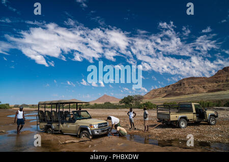 Sauvetage safari véhicule bloqué dans le sable du lit de la rivière Hoarusib, montagnes en arrière-plan, au nord de Sesfontein, Puros, Namibie, Afrique Banque D'Images