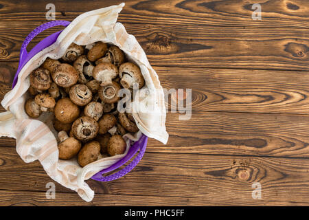 Toute matière première Bella Bébé séchage des champignons dans un tissu placé à l'intérieur d'un bol en plastique violet coloré vu de passage sur une table en bois rustique avec c Banque D'Images