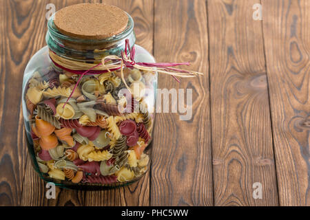 Pot en verre de pâtes macaronis automne dans un assortiment de formes avec un bouchon en liège avec du raphia sur un fond de bois rustique with copy space Banque D'Images