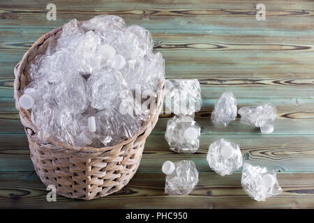 Utilisé froissé des bouteilles en plastique clair propre déborde d'une corbeille à papier en osier sur un plancher de bois rustique vu du dessus dans un c Banque D'Images