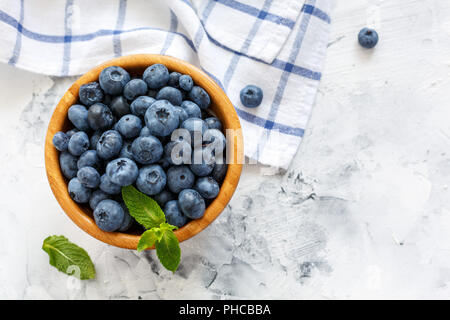 Les bleuets mûrs et la menthe dans un bol en bois. Banque D'Images