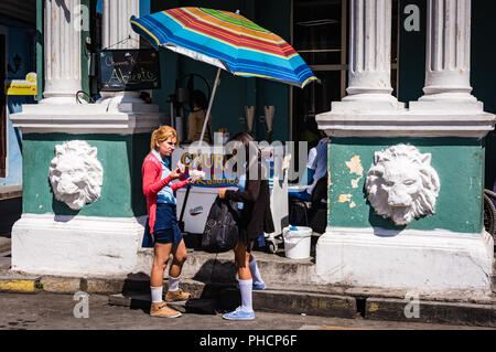 Sancti Spiritus, Cuba / 15 mars 2017 : les écolières en uniforme les collations à l'achat de Cuba un churro devant un bâtiment délabré dans Banque D'Images