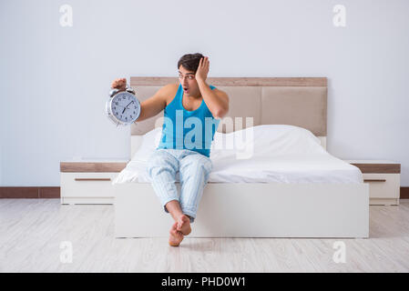 Jeune homme Waking up in bed Banque D'Images