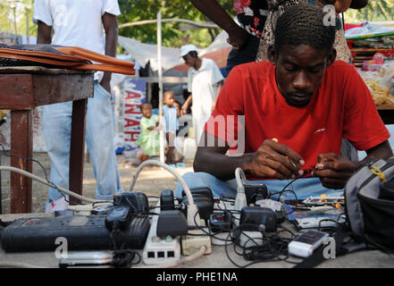 Un homme Haïtiens déplacés fixe téléphones mobiles dans une tente près de la ville, le palais présidentiel à Port-au-Prince, Haïti le 24 janvier 2010. Haïti a été dévastée par un séisme de magnitude 7.0 le 12 janvier 2010 . (U.S. Air Force photo de Tech. Le Sgt. Prentice Colter) (Sortie) Banque D'Images