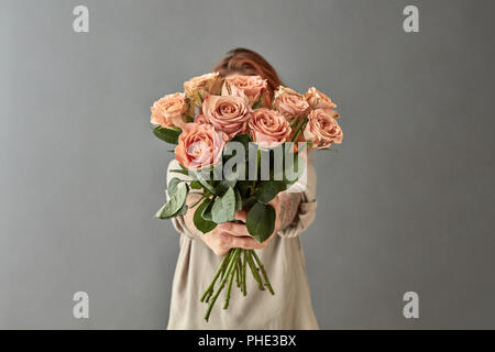 Une femme donne un bouquet de roses beige Banque D'Images