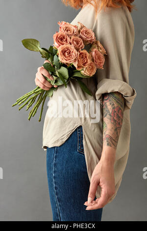 La femme en bleu jeans avec un bouquet de roses beige Banque D'Images