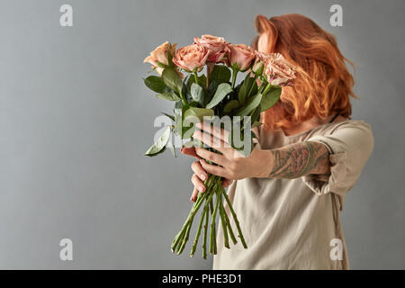 Fille rousse donne un cappuccino roses beige Banque D'Images