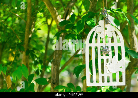 Cage décorative avec un oiseau sur une branche d'arbre dans le jardin Banque D'Images