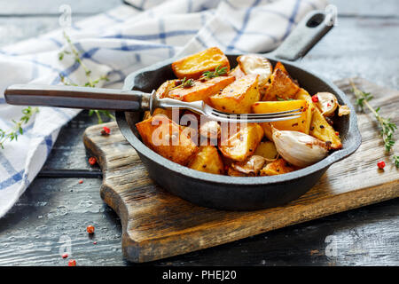 Poêle en fonte avec des tranches de pommes de terre au four. Banque D'Images