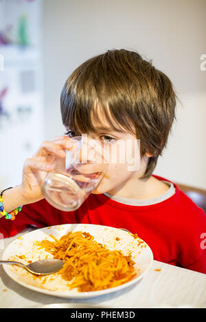 Boire de l'eau et de l'enfant mange du spaghetti Banque D'Images