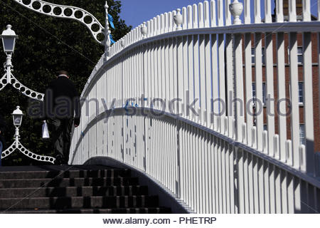 Beau temps à Dublin ce matin comme un homme traverse la Hal'penny Bridge sur la rivière Liffey. Les prévisions sont pour des températures de 17 degrés et mi Banque D'Images