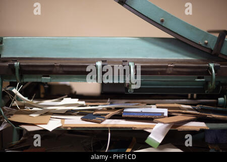 Grande guillotine pour couper du papier avec la lame posée dans un angle faible vue rapprochée sur la table de travail en désordre Banque D'Images