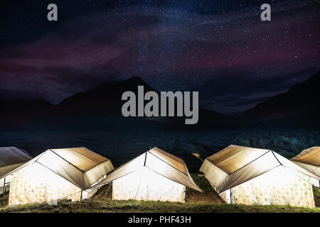 Camping sous ciel coloré plein d'étoiles. Tentes rougeoyant avec ossature montagnes et ciel plein d'étoile au monastère de Rangdum en Inde Banque D'Images