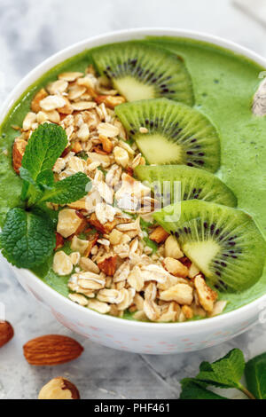 Bol à smoothie aux épinards, granola, kiwi et noix. Banque D'Images