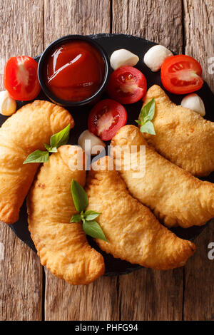 L'Italien panzerotto frits avec une sauce tomate et mozzarella gros plan sur une table en bois. Haut Vertical Vue de dessus Banque D'Images