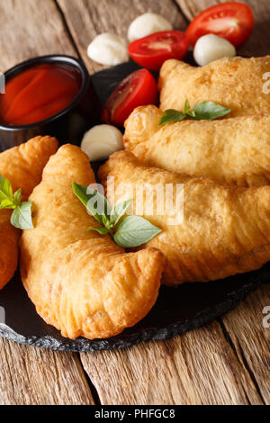 L'Italien panzerotto frits avec une sauce tomate et mozzarella libre sur une table de bois vertical. Banque D'Images