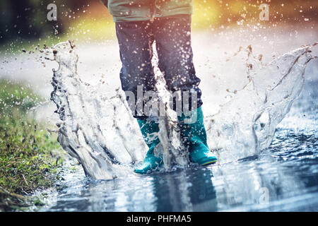 La marche de l'enfant dans la flaque en wellies sur temps de pluie Banque D'Images