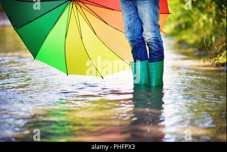 La marche de l'enfant dans la flaque en wellies sur temps de pluie Banque D'Images