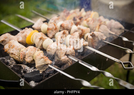 Barbecue en plein air. Barbecue des flammes. Gros plan sur les brochettes, brochettes, cru et cuit. Tranches de viande juteuse de préparer le feu. Banque D'Images