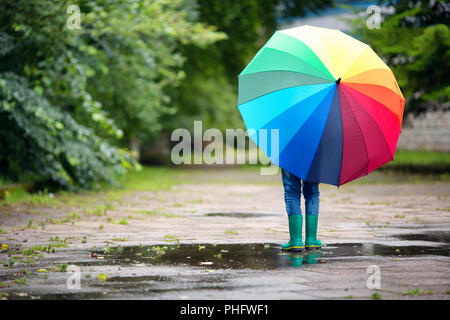 La marche de l'enfant dans la flaque en wellies sur temps de pluie Banque D'Images