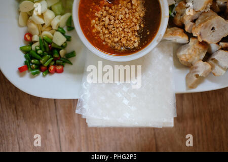 Saucisse de porc haché, de nouilles de riz fermenté et de légumes servi avec la sauce chili. d'été vietnamiens de l'alimentation rouleau appelé Nem Nuong Xa Banque D'Images