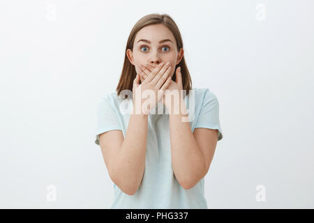 Taille plan sur étonné stupéfait d'apprentissage femme rumeur scandaleuse couvrant la bouche avec les deux paumes regardant étonnés de caméra actuellement impressionné et ravis de poser sur fond gris Banque D'Images