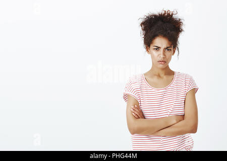 Ne parlons pas de vous entendre, à moins que des excuses. Portrait de bouder mignon femme à la peau sombre en t-shirt à rayures, tenant les mains croisées sur la poitrine, à la recherche de dessous front et les sourcils tout en étant offensé Banque D'Images