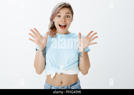 Je suis si heureux, ne peut pas croire. Portrait de surpris et excité de bon à la femme au portrait t-shirt avec bras tatoué et percé le ventre, la paume de bonheur et de sourire Banque D'Images