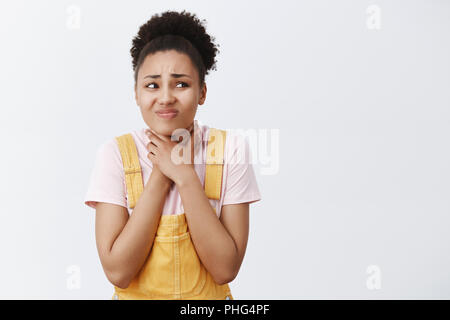 Je ne peux pas respirer, m'aider. Portrait de mécontent mécontent African American girl en salopette jaune, tenant la main sur le cou, à l'étouffement ou de se sentir monter la gorge, gêne et fixant droit Banque D'Images