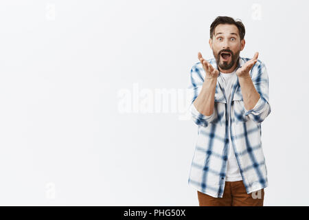 Guy regarder le soccer, ne peux pas croire qu'équipe favorite perdre, l'humiliation de la partition. Bien nerveuse intense mari avec barbe, se serrer la main et à regarder l'appareil photo, posant sur fond gris Banque D'Images