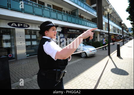Un agent de police se tient sur le Caledonian Road à Islington, au nord de Londres, où un homme a été arrêté après qu'une jeune femme a été poignardé au cours d'une attaque de jour. Banque D'Images