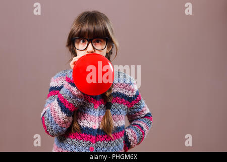 Peu nerdy girl blowing balloon Banque D'Images