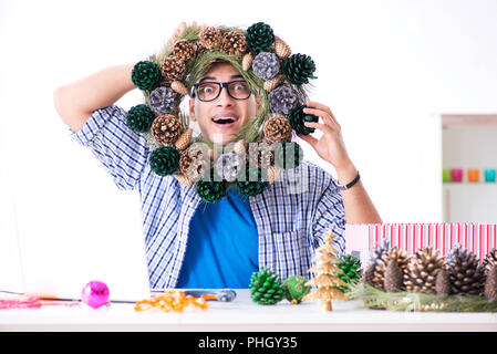 Jeune homme faire de décoration de Noël à partir de cônes Banque D'Images