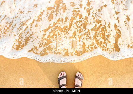 Pieds de femme en sandales sur une plage de sable Banque D'Images