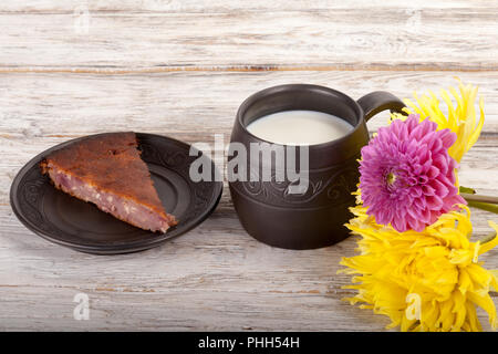 Fait main en céramique mug avec du lait, de fleurs et de pie on wooden table Banque D'Images