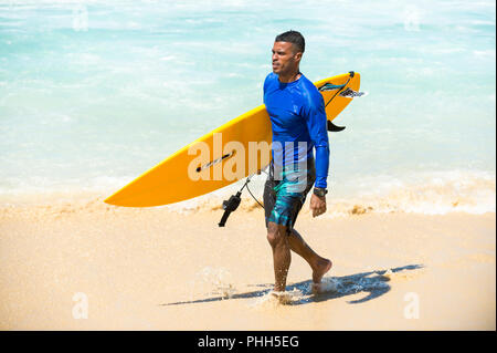 RIO DE JANEIRO - le 9 février 2017 : jeune surfeur brésilien se promène avec son surf à travers les vagues à l'Arpoador, spot de surf populaire. Banque D'Images