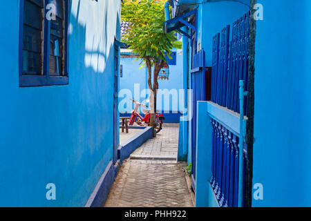 Cour intérieure avec cage à oiseaux sur l'arbre, vélo rétro. Village Kampung Biru avec maisons peintes de couleur bleue est endroit populaire à visiter pour une visite à pied de la ville Banque D'Images