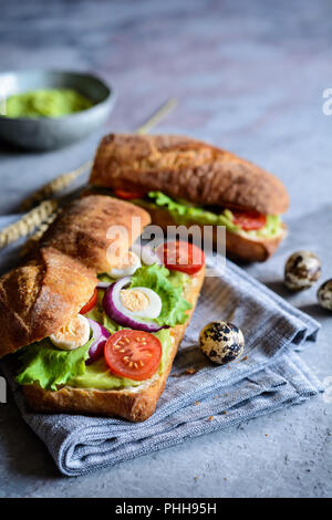 Pain Focaccia avec avocat propagation, laitue, tomate, oignon rouge et des oeufs de cailles Banque D'Images