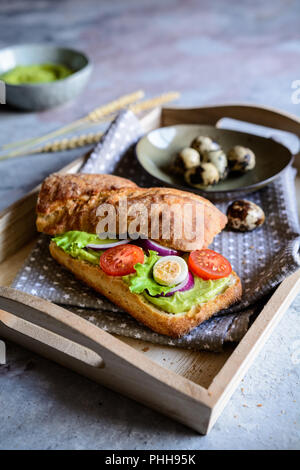 Pain Focaccia avec avocat propagation, laitue, tomate, oignon rouge et des oeufs de cailles Banque D'Images