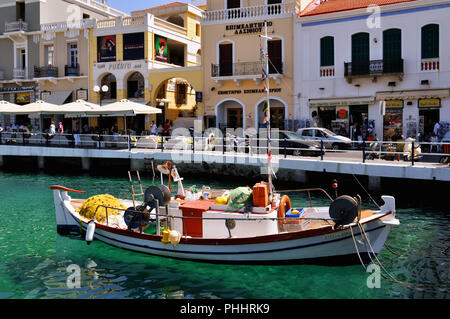 Agios Nikolaos, Crète / Grèce. Bateau de pêche traditionnel sur le lac Voulismeni. Les gens se détendre à la cafétéria et des boutiques de souvenirs Banque D'Images