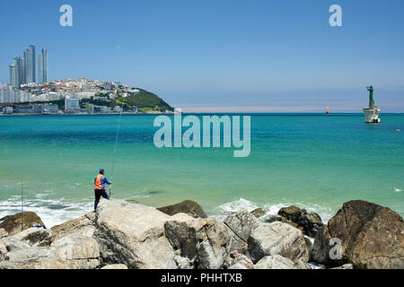 Pêche à la ligne de côte rocheuse de la baie de Haeundae, Busan, Corée - vue de la pointe du parc de Dongbaek. Phare et balise lumineuse visible Banque D'Images