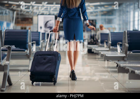 Hôtesse de l'air avec valise passe entre les rangées de sièges dans l'aéroport. Hôtesse de l'agent de bord avec des bagages, avec un bagage à main, d'aviatransportations Banque D'Images