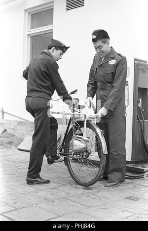 1950s vélos supplémentaires. Le fabricant allemand de cyclomoteurs et de moteurs Victoria fournit ce moteur d'aide de bicyclette appelé Vicky. Il peut être monté sur n'importe quelle roue arrière de vélo en tant qu'équipement supplémentaire. Il a 2 ch et deux pignons. Lorsqu'il est utilisé, il n'y a pas de taxe ou de permis de conduire neccesary. Pour l'achat d'un vélo et d'un moteur en même temps, le prix est de 690 sek. Ici, le jeune adolescent qui obtient le réservoir de gaz rempli à une station de gaz Esso. Suède 1953 photo Kristoffersson 1-1 Banque D'Images