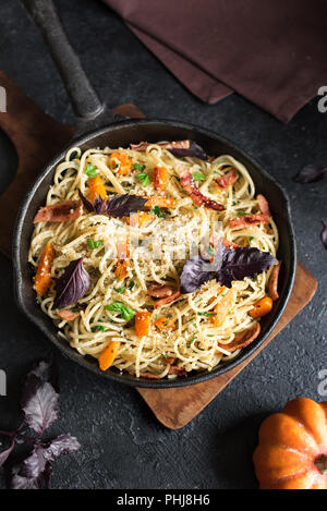 L'automne des pâtes avec du bacon et de citrouille dans poêle en fonte. Pâtes potiron spaghetti fait maison sur noir, copiez l'espace. L'alimentation de l'automne. Banque D'Images