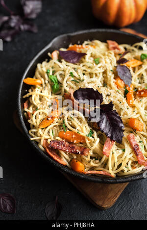 L'automne des pâtes avec du bacon et de citrouille dans poêle en fonte. Spaghetti maison pâtes potiron avec bacon, fromage parmesan et basilic sur noir, copiez l'espace. Aut Banque D'Images