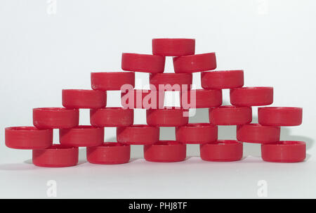 Modèle mur holey de plastique ondulé rouge des capsules de bouteille, s'appuyant sur l'autre par l'extrémité des bords étroits. plié, en couches dans les rangées Banque D'Images