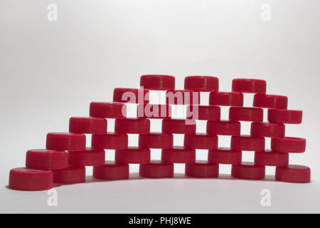 Mur avec des trous modèle. faites de plastique ondulé rouge des capsules de bouteille, empilés en rangées. faible profondeur de champ. focus à l'avant de l'élément d'égalité Banque D'Images