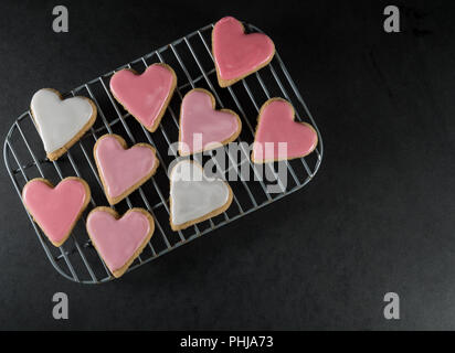 Petit coeur givré Les Cookies sur une grille au-dessus de la surface de l'ardoise Banque D'Images